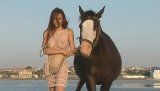 Awesome young brunette wearing sexy fishnet is riding horse outdoors. She is demonstrating her perfect bump and sensational boobs with pleasure.