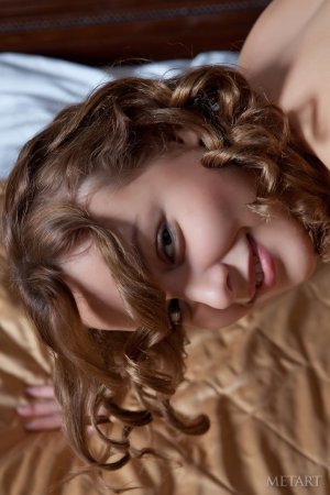 A curly brunette poses on the bed sheets photo 15